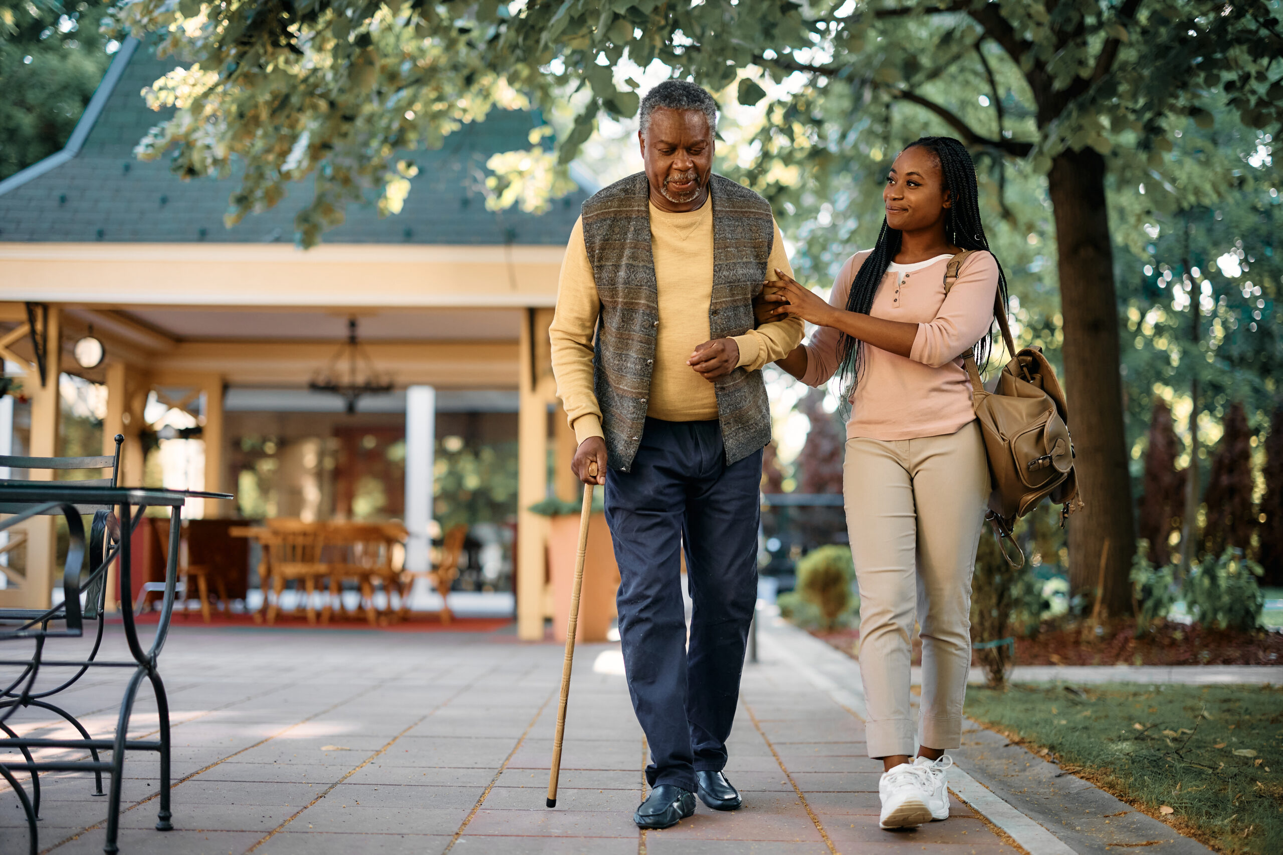 Smiling woman walks with her senior father outside of restaurant