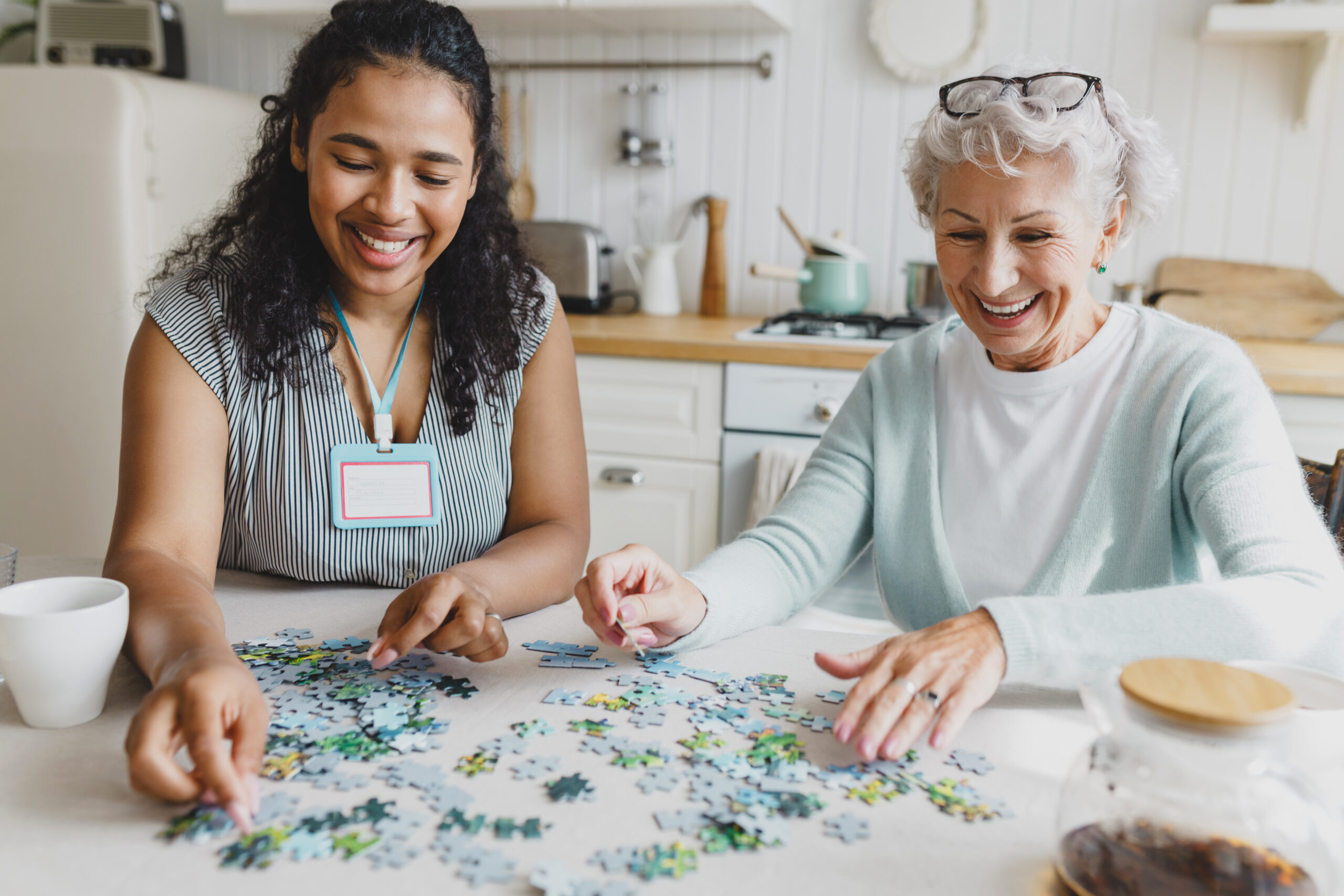 Smiling senior woman working on puzzle with caregiver