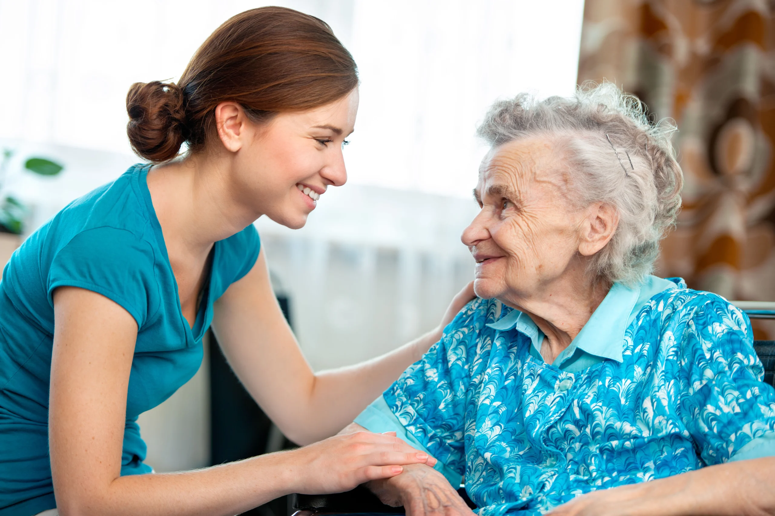 Seated senior woman leaning in and talking to caregiver.