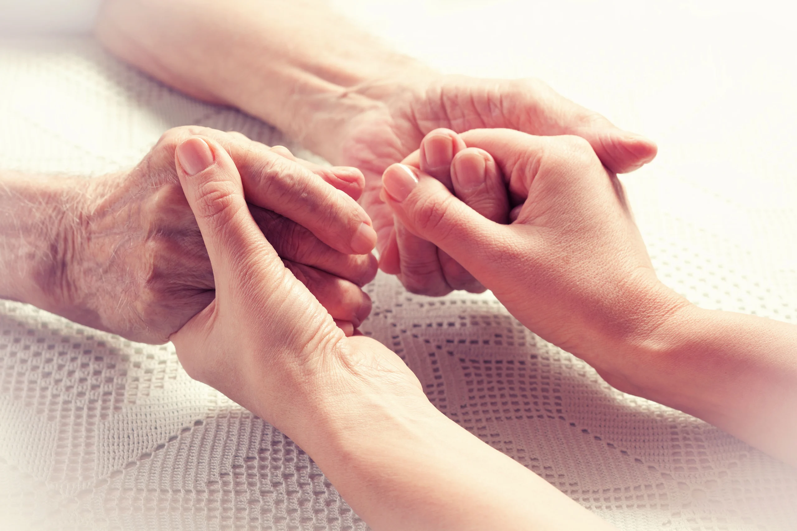 Close up of senior's hands being held by younger person.