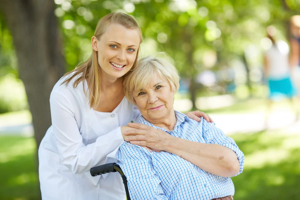 Senior woman leaning back against younger woman while both are posed outdoors.