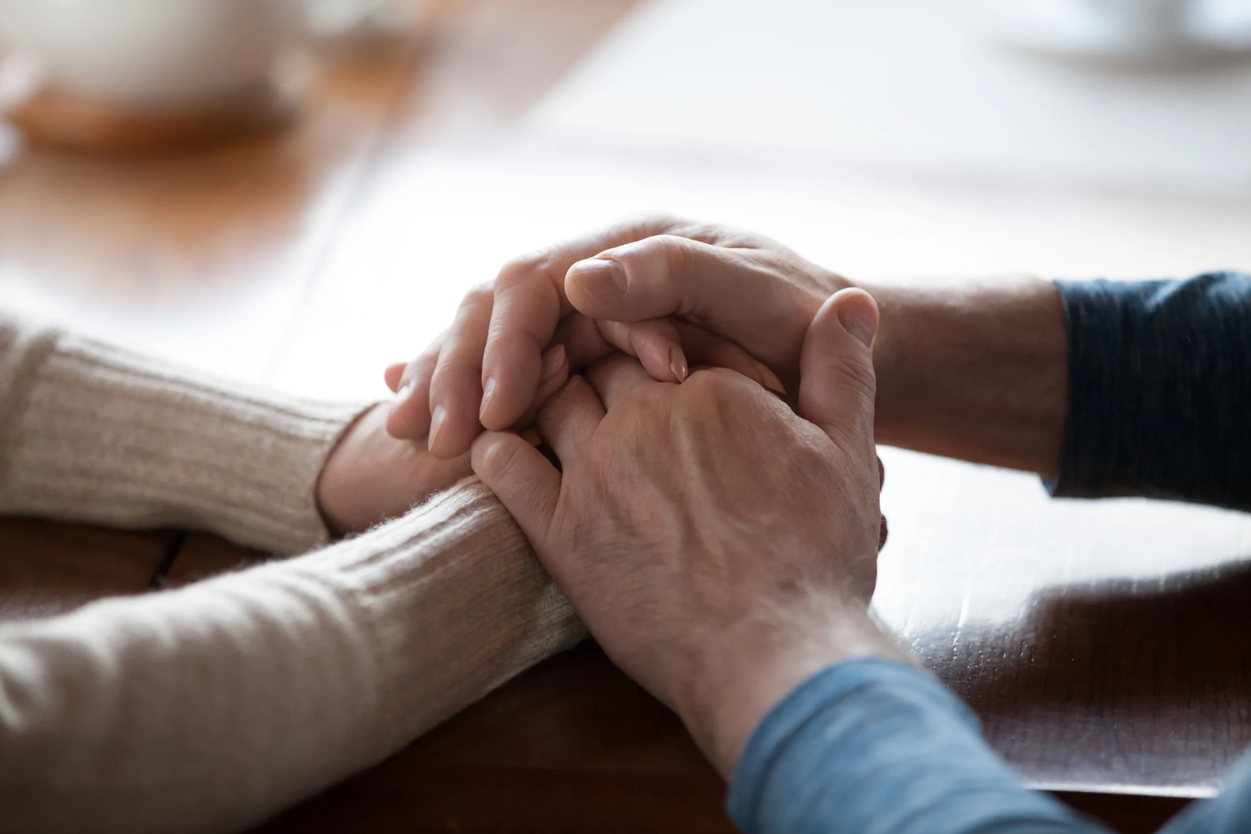 Closeup of caregiver and patient holding hands